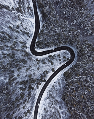 top-down-aerial-view-winding-road-int-he-middle-trees-snow